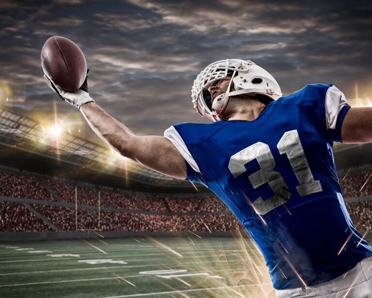 Football Player with a Blue Uniform Catching a Ball in a Stadium