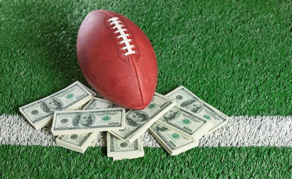NFL Football Sitting with-piles-of-dollars on AstroTurf
